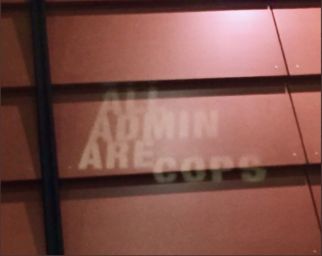 a projection on the wall of the Mondavi Center reading "All Admin Are Cops" during the UC Davis "Three Presidents/One Chancellor" event 2/24/22
