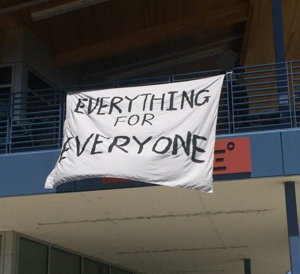 A photo of a banner hanging from the balcony of Latitude Dining Commons. The banner reads "everything for everyone"