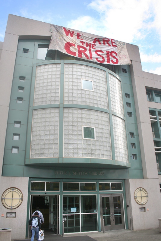 entrance to Shields LIbrary with "We are the crisis" banner dropped