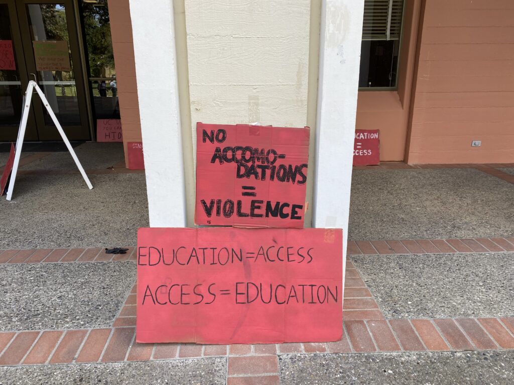 signs at Mrak hall reading "No accommodations = violence"; "education = access/access = education"