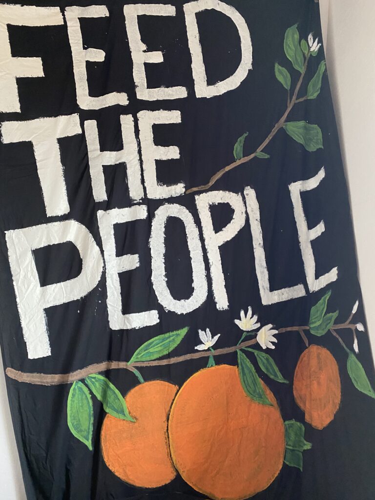 black banner reading "feed the people" with oranges under it